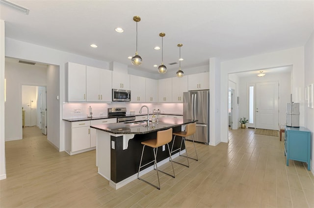 3602 Secret Stroll Dr, Sarasota, FL 34240 - kitchen with appliances with stainless steel finishes, a breakfast bar, light wood-type flooring, recessed lighting, and a center island with sink