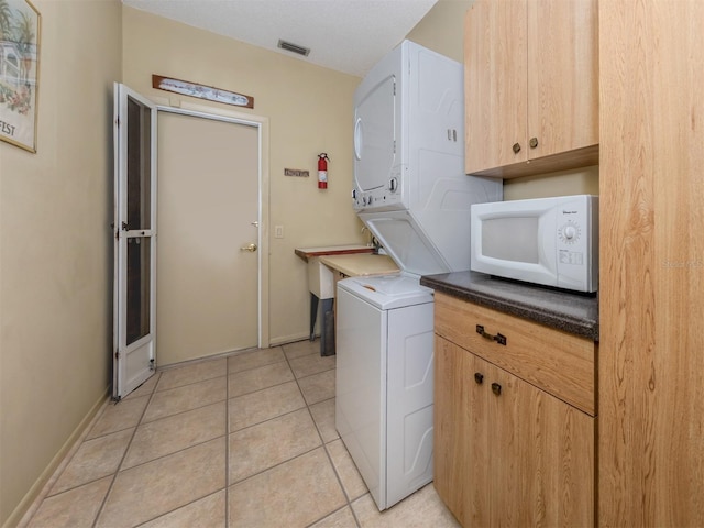 154 Inlets Blvd, Nokomis, FL 34275 - laundry area with stacked washer / drying machine, light tile patterned floors, and cabinet space