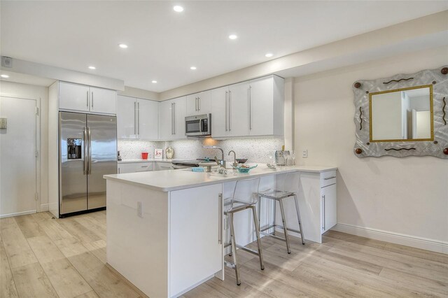 1000 Longboat Club Rd Unit 1105, Longboat Key, FL 34228 - kitchen with stainless steel appliances, light wood-type flooring, a peninsula, light countertops, and backsplash