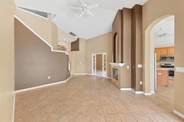 12342 Lavender Loop, Bradenton, FL 34212 - unfurnished living room featuring a ceiling fan, high vaulted ceiling, light tile patterned floors, arched walkways, and a fireplace