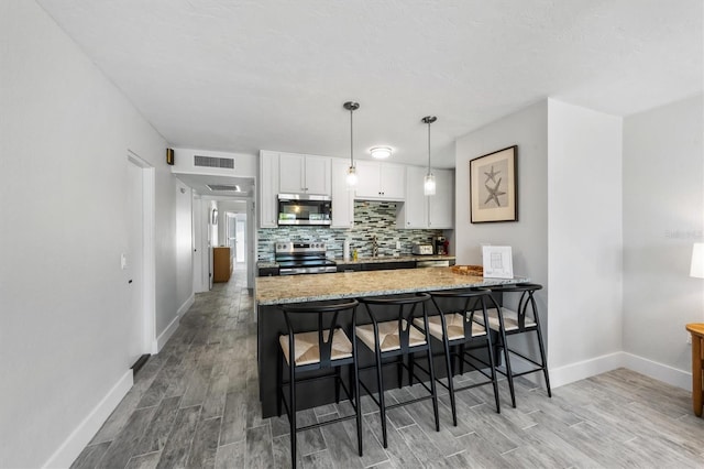441 62nd St, Holmes Beach, FL 34217 - kitchen featuring appliances with stainless steel finishes, light wood-style flooring, tasteful backsplash, and white cabinetry