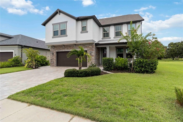 731 116th Ct NE, Bradenton, FL 34212 - view of front of home with stucco siding, stone siding, a front lawn, an attached garage, and decorative driveway