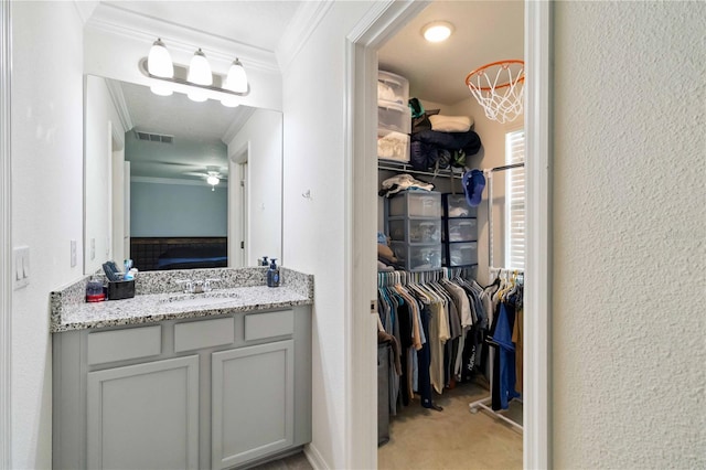 731 116th Ct NE, Bradenton, FL 34212 - bathroom with ornamental molding, vanity, a walk in closet, a textured wall, and a ceiling fan