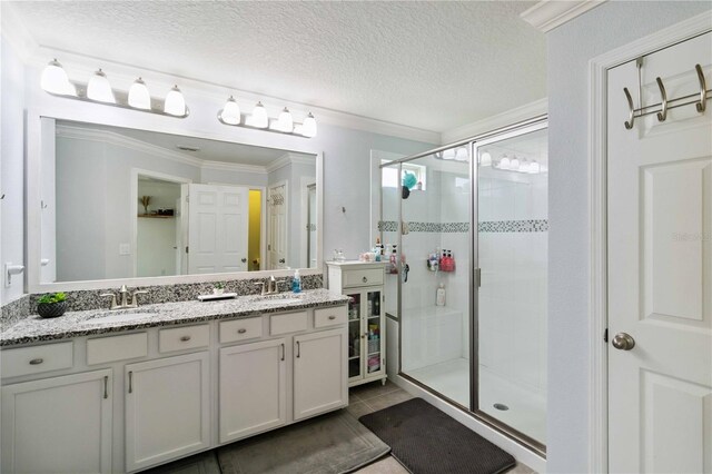 731 116th Ct NE, Bradenton, FL 34212 - bathroom with a shower stall, double vanity, a textured ceiling, ornamental molding, and tile patterned floors