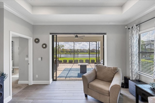 12641 Coastal Breeze Way, Bradenton, FL 34211 - living area with a tray ceiling, ceiling fan, wood tiled floors, a water view, and crown molding