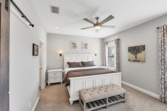 12641 Coastal Breeze Way, Bradenton, FL 34211 - bedroom featuring a barn door, light colored carpet, a textured ceiling, a ceiling fan, and recessed lighting