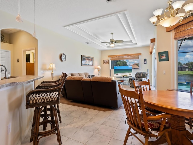 280 Dahlia Ct, Bradenton, FL 34212 - dining room featuring a raised ceiling, a ceiling fan, light tile patterned floors, arched walkways, and a chandelier