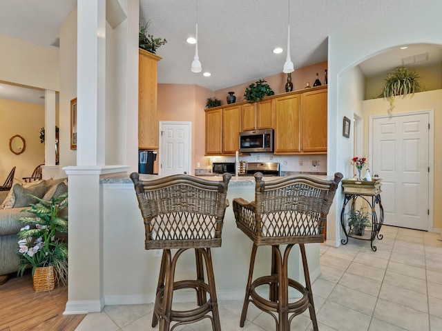 280 Dahlia Ct, Bradenton, FL 34212 - kitchen featuring stainless steel microwave, recessed lighting, electric range, light tile patterned flooring, and ornate columns