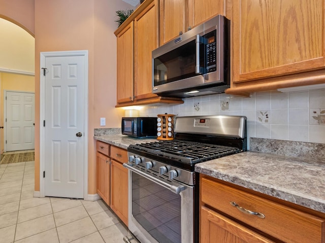 280 Dahlia Ct, Bradenton, FL 34212 - kitchen with stainless steel appliances, light tile patterned floors, tasteful backsplash, and brown cabinetry