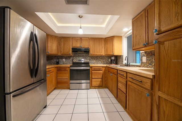 1208 Francis Ave, Sarasota, FL 34232 - kitchen featuring stainless steel appliances, range hood, brown cabinetry, decorative backsplash, and a tray ceiling