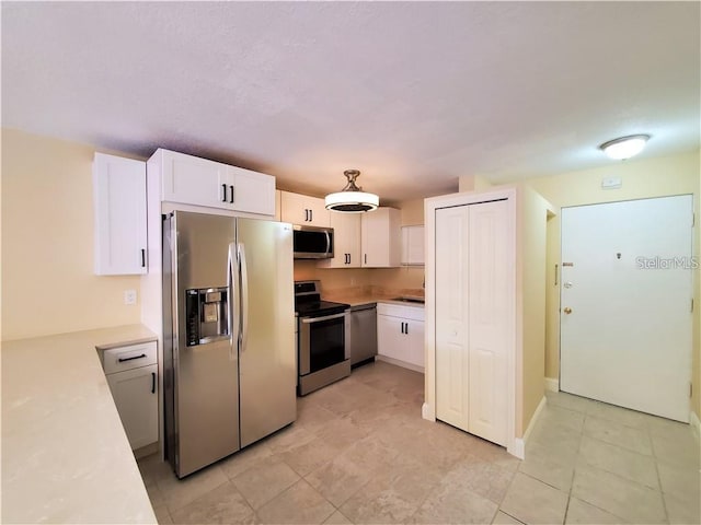 2763 Woodgate Ln Unit 105, Sarasota, FL 34231 - kitchen featuring appliances with stainless steel finishes, light countertops, white cabinetry, and light tile patterned floors