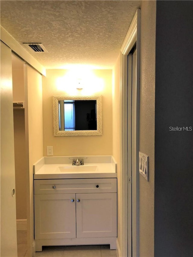 2763 Woodgate Ln Unit 105, Sarasota, FL 34231 - bathroom with vanity, a textured ceiling, and tile patterned flooring