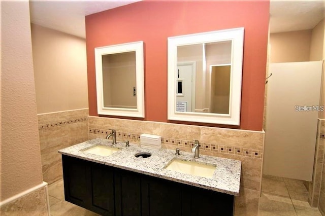 2763 Woodgate Ln Unit 105, Sarasota, FL 34231 - bathroom with double vanity, tile walls, tile patterned flooring, and wainscoting