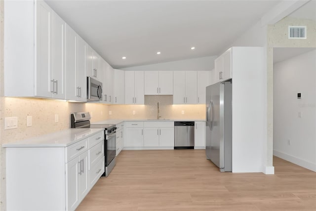 4515 19th Ave W, Bradenton, FL 34209 - kitchen featuring appliances with stainless steel finishes, backsplash, light wood-style floors, lofted ceiling, and light countertops