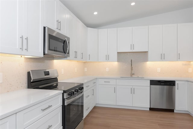 4515 19th Ave W, Bradenton, FL 34209 - kitchen with stainless steel appliances, white cabinetry, light countertops, backsplash, and vaulted ceiling