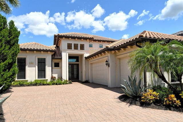 7638 Windy Hill Cv, Bradenton, FL 34202 - mediterranean / spanish-style home featuring an attached garage, a tiled roof, french doors, and stucco siding