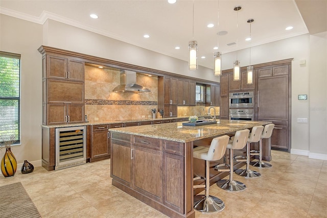 7638 Windy Hill Cv, Bradenton, FL 34202 - kitchen featuring wine cooler, wall chimney exhaust hood, decorative backsplash, an island with sink, and crown molding