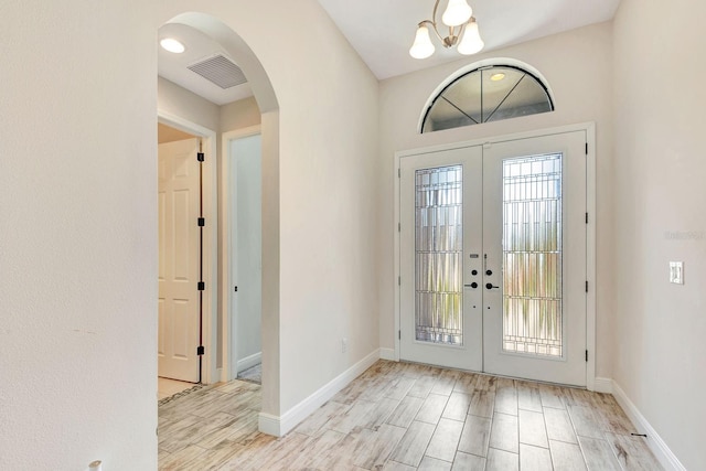 9215 Isabella Cir, Parrish, FL 34219 - entryway with french doors, arched walkways, wood finished floors, and a chandelier