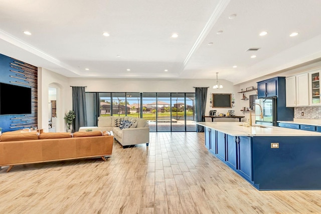 9215 Isabella Cir, Parrish, FL 34219 - kitchen with blue cabinets, light countertops, light wood-style flooring, a raised ceiling, and recessed lighting