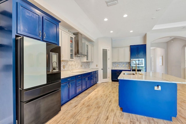 9215 Isabella Cir, Parrish, FL 34219 - kitchen featuring wall chimney exhaust hood, freestanding refrigerator, electric stovetop, a kitchen island with sink, and blue cabinets