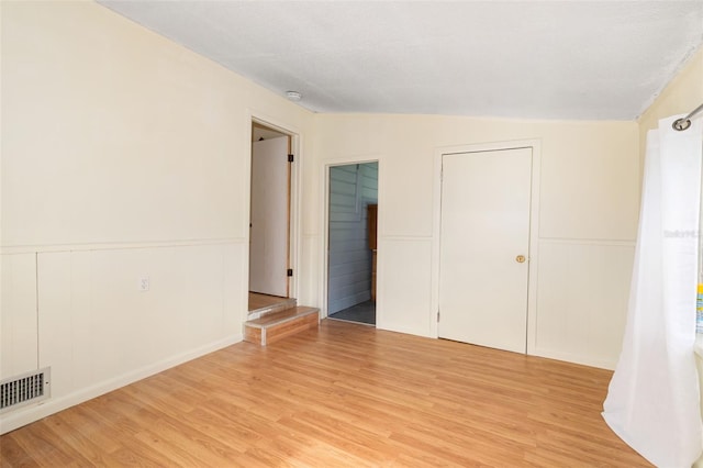 3020 51st Ave E, Bradenton, FL 34203 - empty room featuring light wood-style floors, a decorative wall, and a wainscoted wall