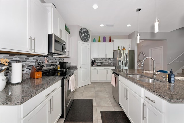5134 Jackel Chase Dr, Wimauma, FL 33598 - kitchen featuring appliances with stainless steel finishes, backsplash, a center island with sink, light tile patterned floors, and white cabinets