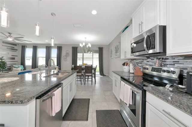 5134 Jackel Chase Dr, Wimauma, FL 33598 - kitchen with appliances with stainless steel finishes, backsplash, light tile patterned flooring, white cabinets, and dark stone countertops