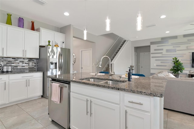 5134 Jackel Chase Dr, Wimauma, FL 33598 - kitchen featuring stainless steel appliances, open floor plan, light tile patterned floors, white cabinetry, and decorative backsplash