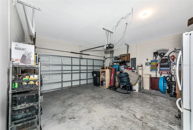 5134 Jackel Chase Dr, Wimauma, FL 33598 - garage with a garage door opener, concrete block wall, freestanding refrigerator, and electric panel