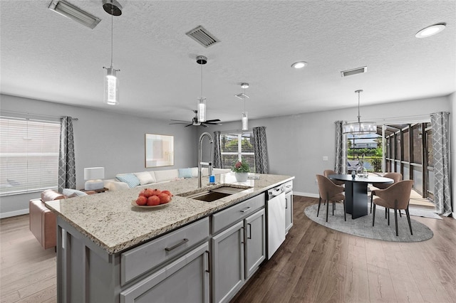 7036 Chatum Light Run, Bradenton, FL 34212 - kitchen with wood finished floors, open floor plan, a center island with sink, light stone countertops, and a textured ceiling