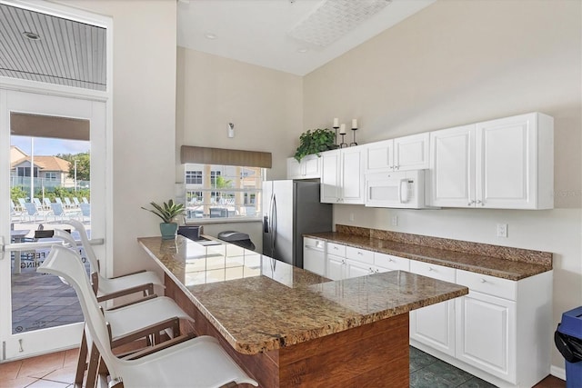 8335 Glenrose Way Unit 1513, Sarasota, FL 34238 - kitchen with white microwave, stainless steel fridge with ice dispenser, a high ceiling, healthy amount of natural light, and tile patterned floors