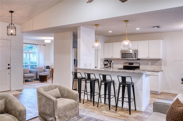 4204 Malickson Dr, Parrish, FL 34219 - kitchen with stainless steel microwave, range with electric stovetop, open floor plan, a kitchen breakfast bar, and tasteful backsplash