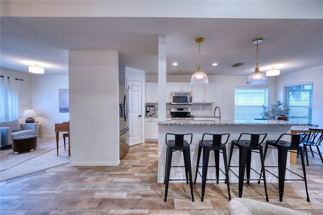 4204 Malickson Dr, Parrish, FL 34219 - kitchen featuring stainless steel appliances, white cabinetry, a kitchen breakfast bar, light wood finished floors, and a kitchen island with sink