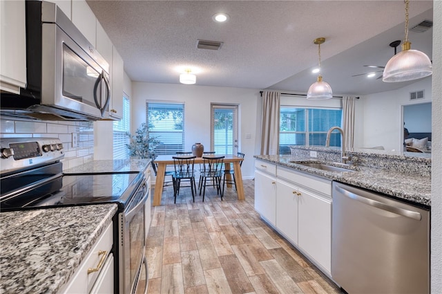 4204 Malickson Dr, Parrish, FL 34219 - kitchen featuring appliances with stainless steel finishes, light wood-style floors, white cabinets, a textured ceiling, and backsplash
