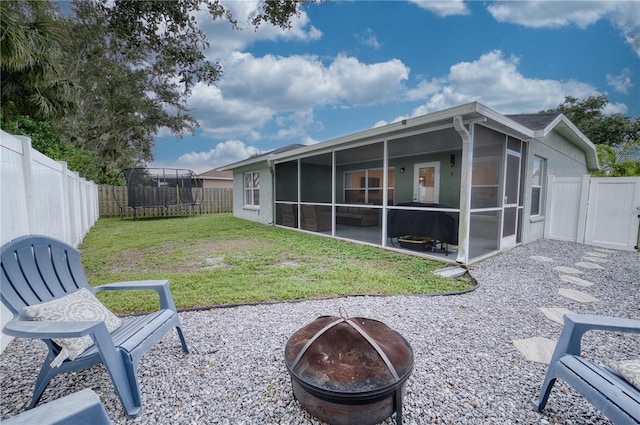 4204 Malickson Dr, Parrish, FL 34219 - rear view of property featuring a trampoline, a fire pit, a sunroom, a fenced backyard, and a patio area