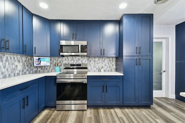 303 45th St W, Bradenton, FL 34209 - kitchen featuring appliances with stainless steel finishes, blue cabinets, light wood-style flooring, a textured ceiling, and recessed lighting