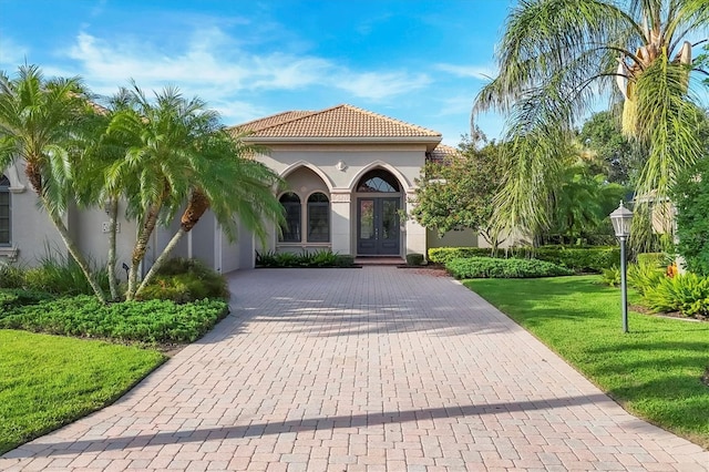 13818 Milan Ter, Lakewood Ranch, FL 34202 - view of front of house with stucco siding, a front yard, decorative driveway, and french doors
