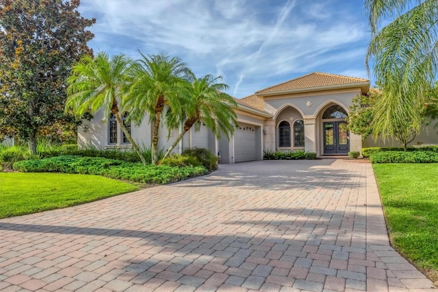 13818 Milan Ter, Lakewood Ranch, FL 34202 - mediterranean / spanish house featuring french doors, an attached garage, decorative driveway, stucco siding, and a front yard
