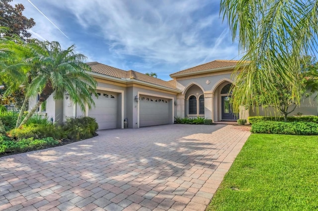13818 Milan Ter, Lakewood Ranch, FL 34202 - mediterranean / spanish house featuring stucco siding, a garage, driveway, and a front lawn