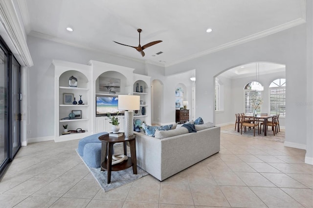 13818 Milan Ter, Lakewood Ranch, FL 34202 - living room featuring light tile patterned flooring, ornamental molding, a ceiling fan, built in shelves, and arched walkways