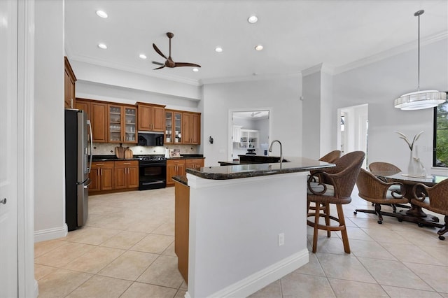 13818 Milan Ter, Lakewood Ranch, FL 34202 - kitchen featuring black appliances, brown cabinets, light tile patterned floors, crown molding, and a kitchen breakfast bar