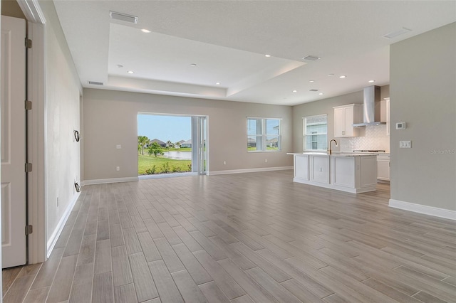 14312 Skipping Stone Loop, Parrish, FL 34219 - unfurnished living room with a tray ceiling, light wood-type flooring, and recessed lighting