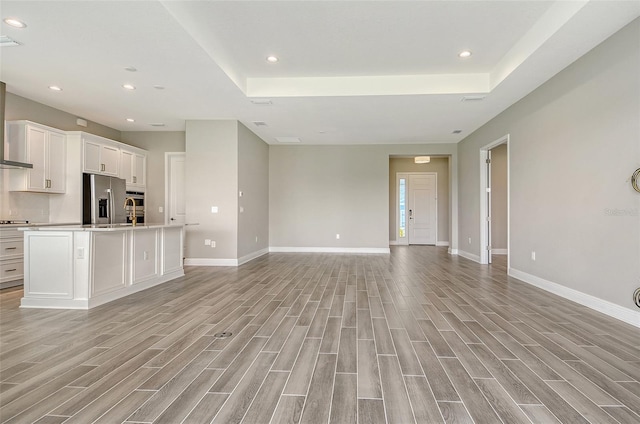 14312 Skipping Stone Loop, Parrish, FL 34219 - unfurnished living room with light wood-type flooring, recessed lighting, and a tray ceiling
