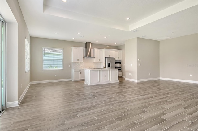 14312 Skipping Stone Loop, Parrish, FL 34219 - unfurnished living room featuring light wood-type flooring, a tray ceiling, and recessed lighting