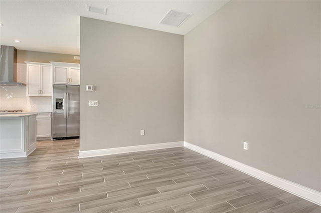 14312 Skipping Stone Loop, Parrish, FL 34219 - kitchen featuring stainless steel appliances, wall chimney exhaust hood, light wood finished floors, white cabinets, and light countertops