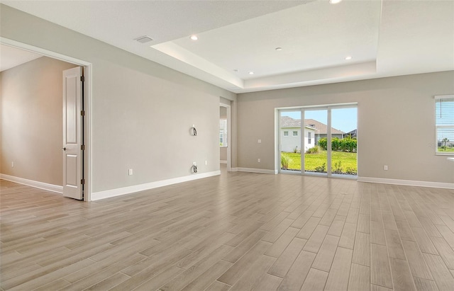 14312 Skipping Stone Loop, Parrish, FL 34219 - empty room featuring a raised ceiling, light wood-style flooring, recessed lighting, and plenty of natural light