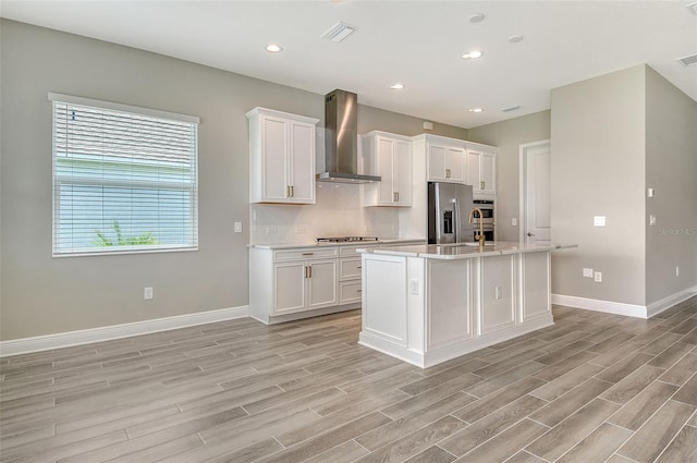 14312 Skipping Stone Loop, Parrish, FL 34219 - kitchen featuring wall chimney range hood, appliances with stainless steel finishes, light wood-type flooring, light countertops, and white cabinetry