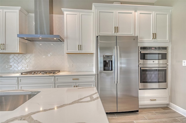 14312 Skipping Stone Loop, Parrish, FL 34219 - kitchen with appliances with stainless steel finishes, wall chimney range hood, white cabinetry, tasteful backsplash, and wood tiled floors