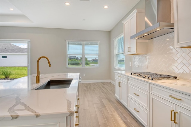 14312 Skipping Stone Loop, Parrish, FL 34219 - kitchen with wall chimney range hood, stainless steel gas stovetop, light wood-type flooring, backsplash, and recessed lighting