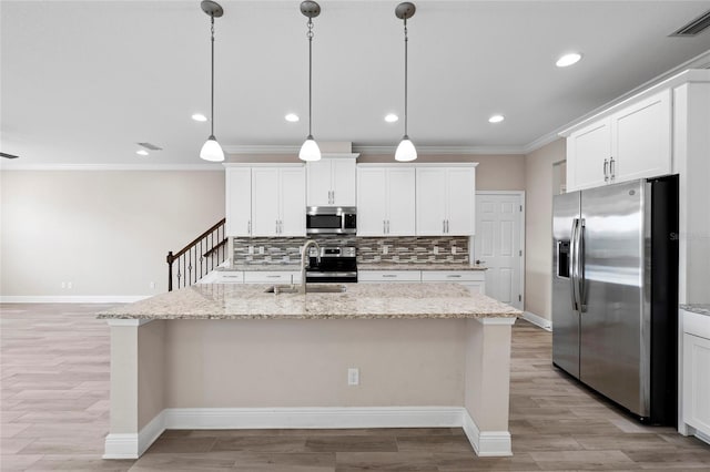 5174 78th St Cir E, Bradenton, FL 34203 - kitchen featuring appliances with stainless steel finishes, ornamental molding, backsplash, white cabinets, and a kitchen island with sink